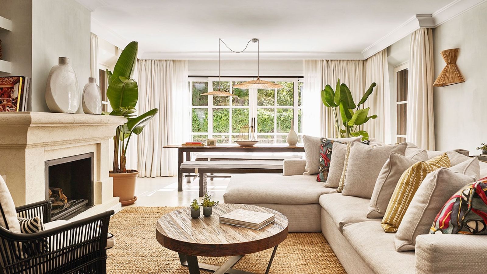 Four-bedroom Villa living area with large linen sectional, jute rug, rustic wood table, and fireplace at Marbella Club