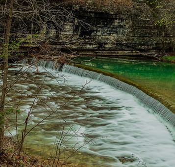 Serene waterfall cascades into a calm green pool in Little blue state park at Shangri-La Monkey Island