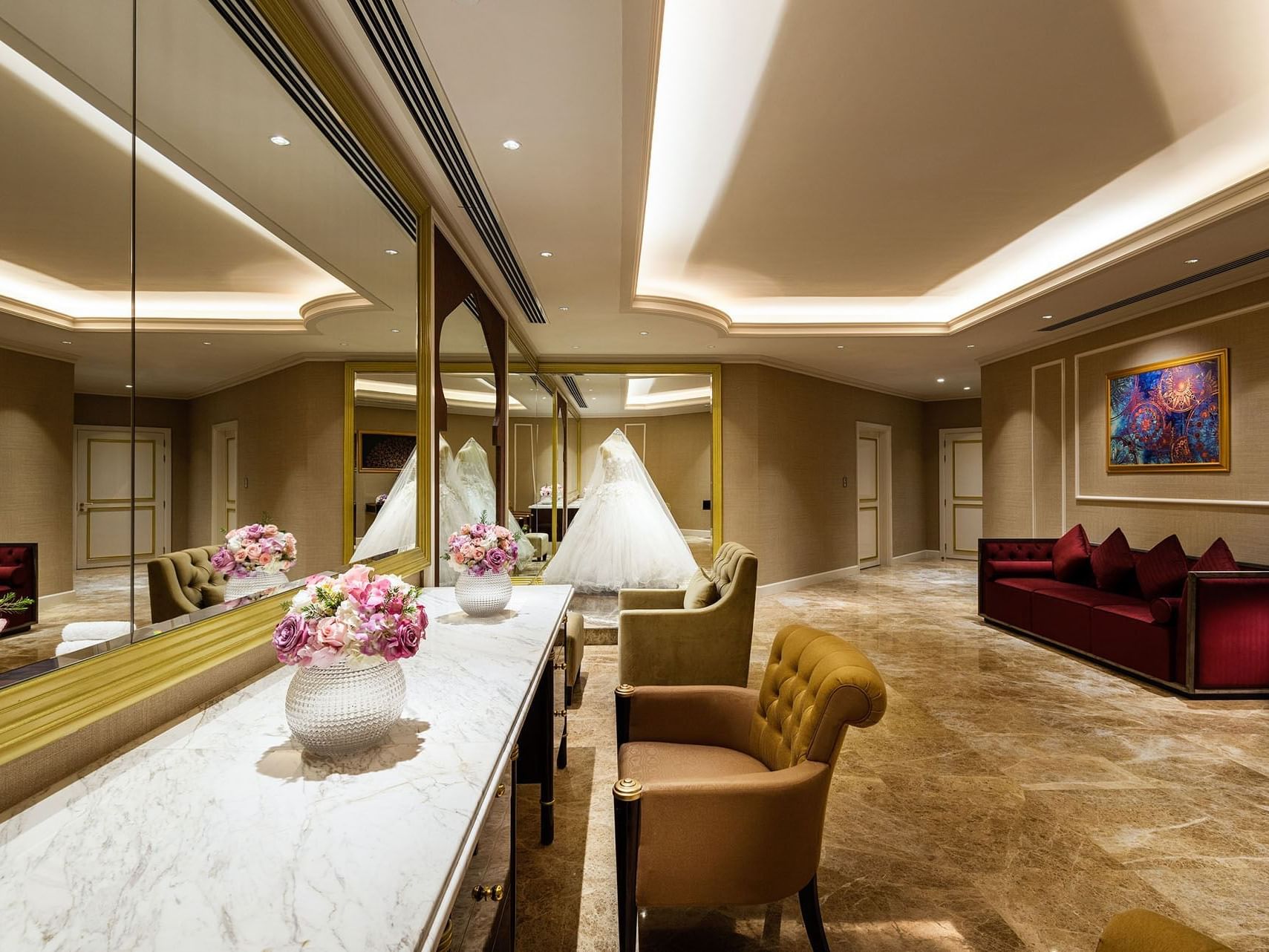 Bridal salon with large mirrors, couches, chairs, and a marble table with floral arrangements.