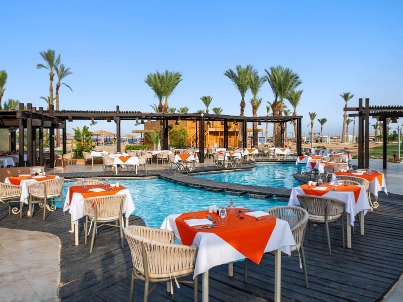 منطقة لتناول الطعام في الهواء الطلق بجانب المسبح مع طاولات مجهزة في مطعم Cardamom، فندق Pickalbatros Sands في بورت غالب.
