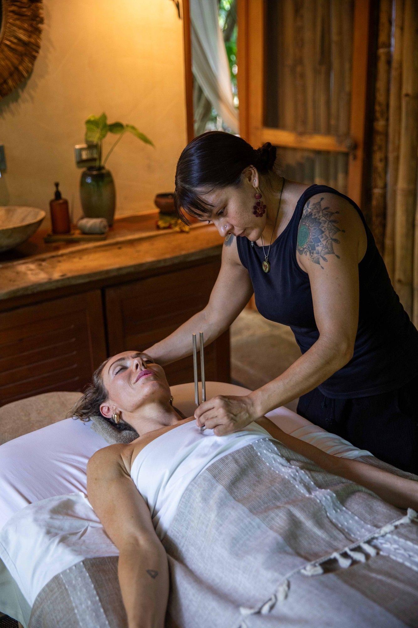 Holistic tuning fork therapy featuring a therapist and guest in Lahari Wellness Center at Cala Luna Boutique Hotel