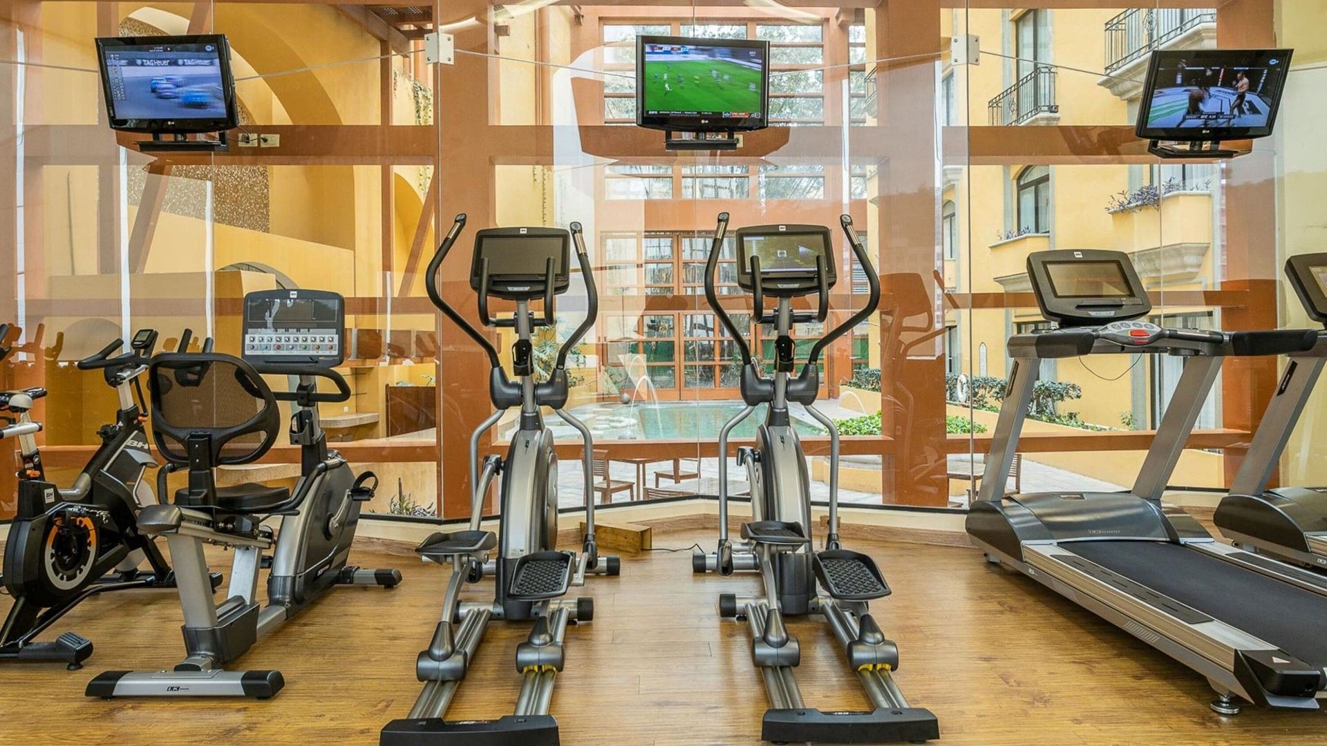 Modern fitness center with treadmills and ellipticals overlooking the courtyard at Quinta Real Monterrey