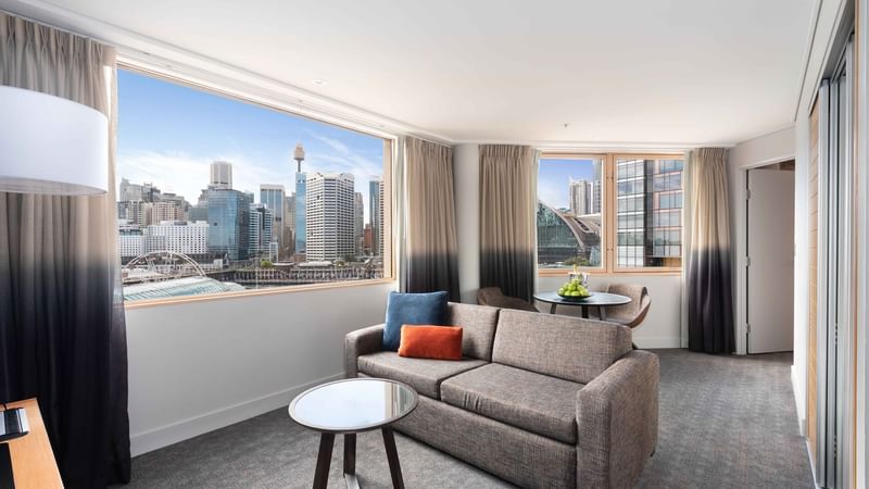 Living area with a brown couch and Darling Harbour view in Executive Suite at Novotel Sydney on Darling Harbour