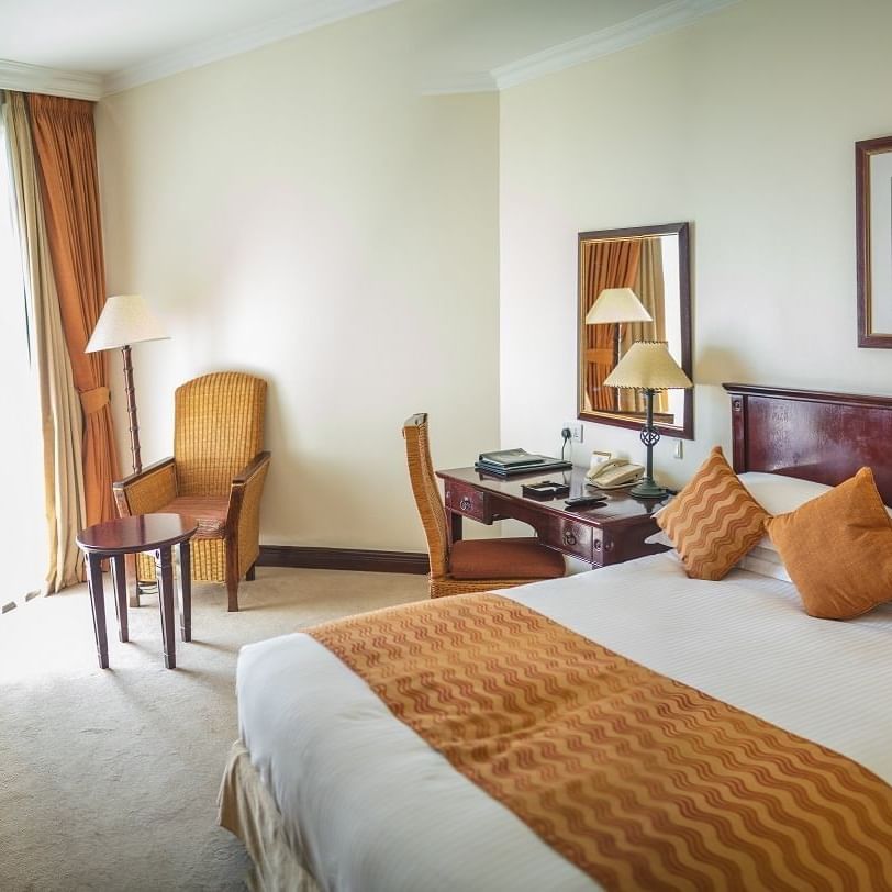 Elegant Superior Room with a large bed, desk, chair, and balcony at Lake Kivu Serena Hotel in Gisenyi.