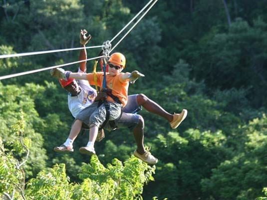 Two people ziplining at jungle canopy zipline near Infinity Bay