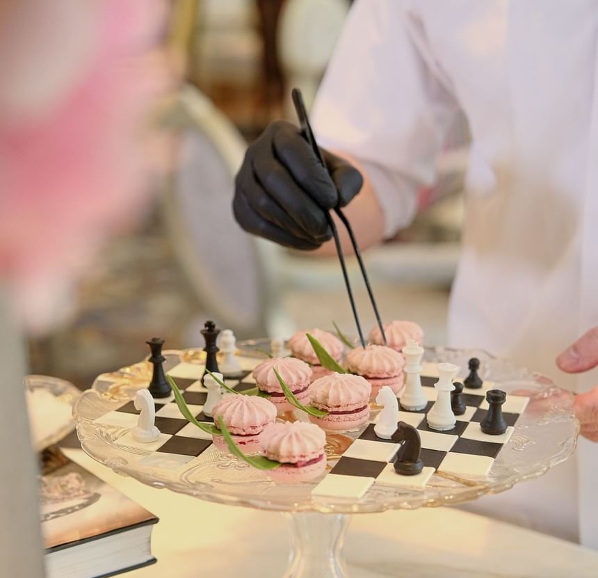 Chef arranging pink macarons on a chessboard cake stand in Park Lounge at Park Hyatt Saigon
