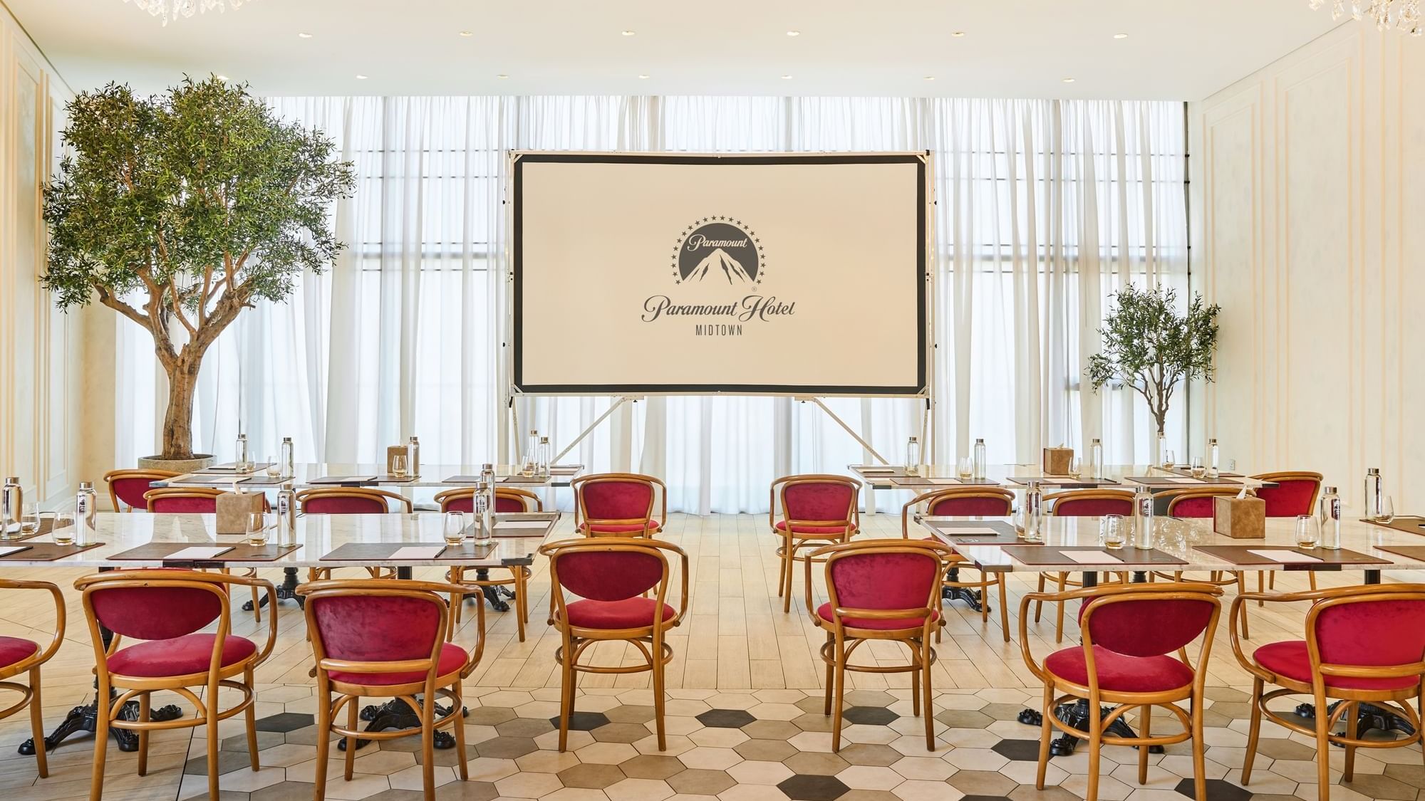 Meeting room at Paparazzi restaurant venue, Paramount Hotel Midtown, set up with tables facing a large projector screen
