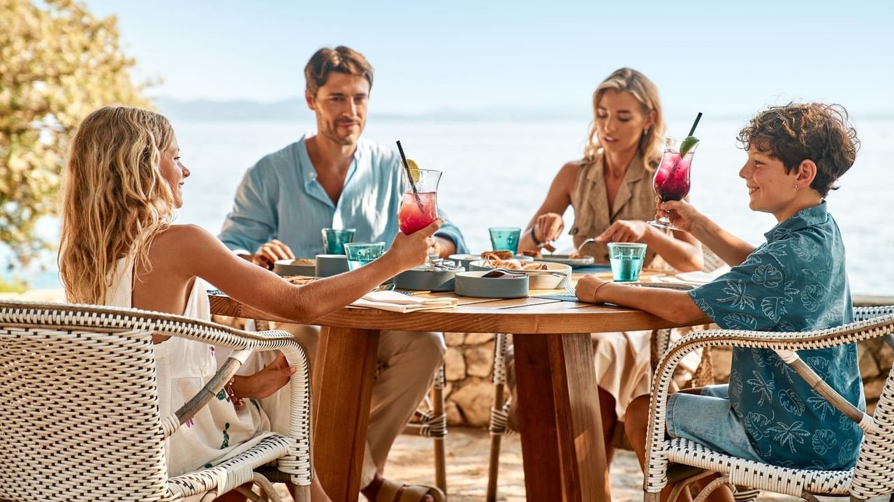 Familie genießt ein Essen am Strand mit Getränken und Meeresblick.