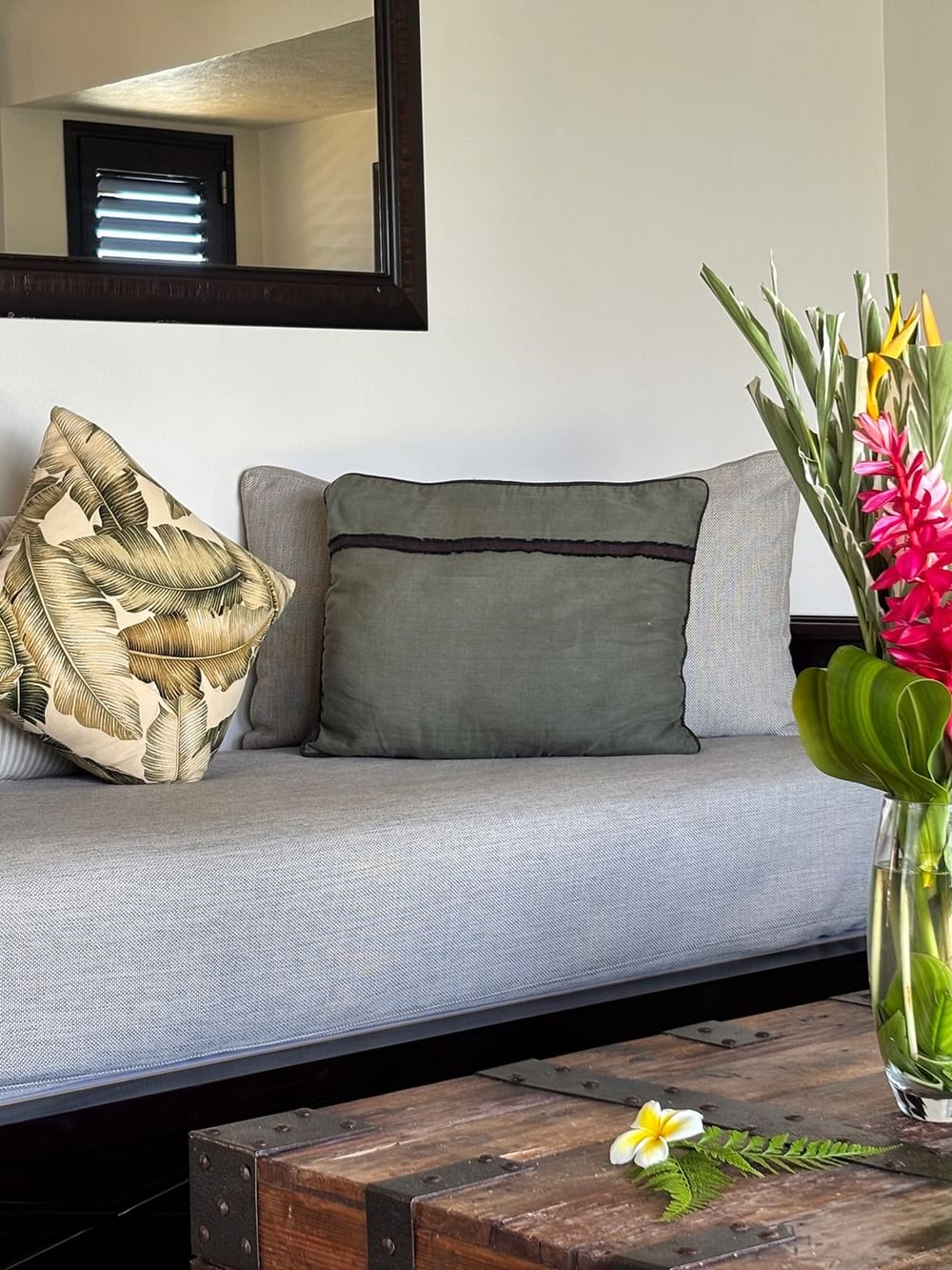Cozy couch with tropical pillows and vibrant flowers on a wooden table at Warwick Le Lagon in Efate.