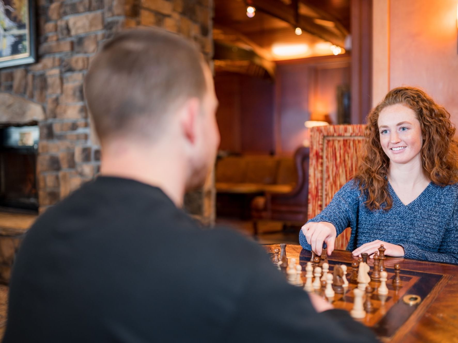 A couple playing chess on a wooden board at High Peaks Resort