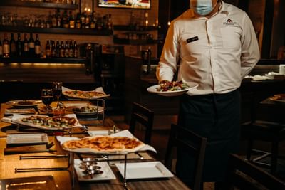 Waiter serving meals in Italiano Cucina at Araiza Hotel Calafia
