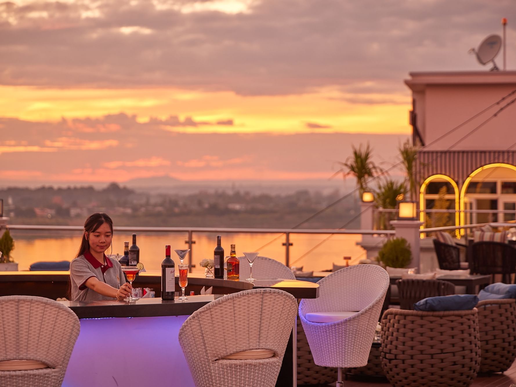 Rooftop bar setting with outdoor furniture overlooking a sunset sky at Eastin Hotels