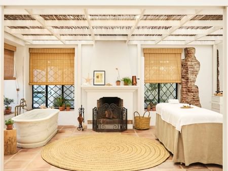 Spa room with bathtub, fireplace, and massage table for couples to relax together.