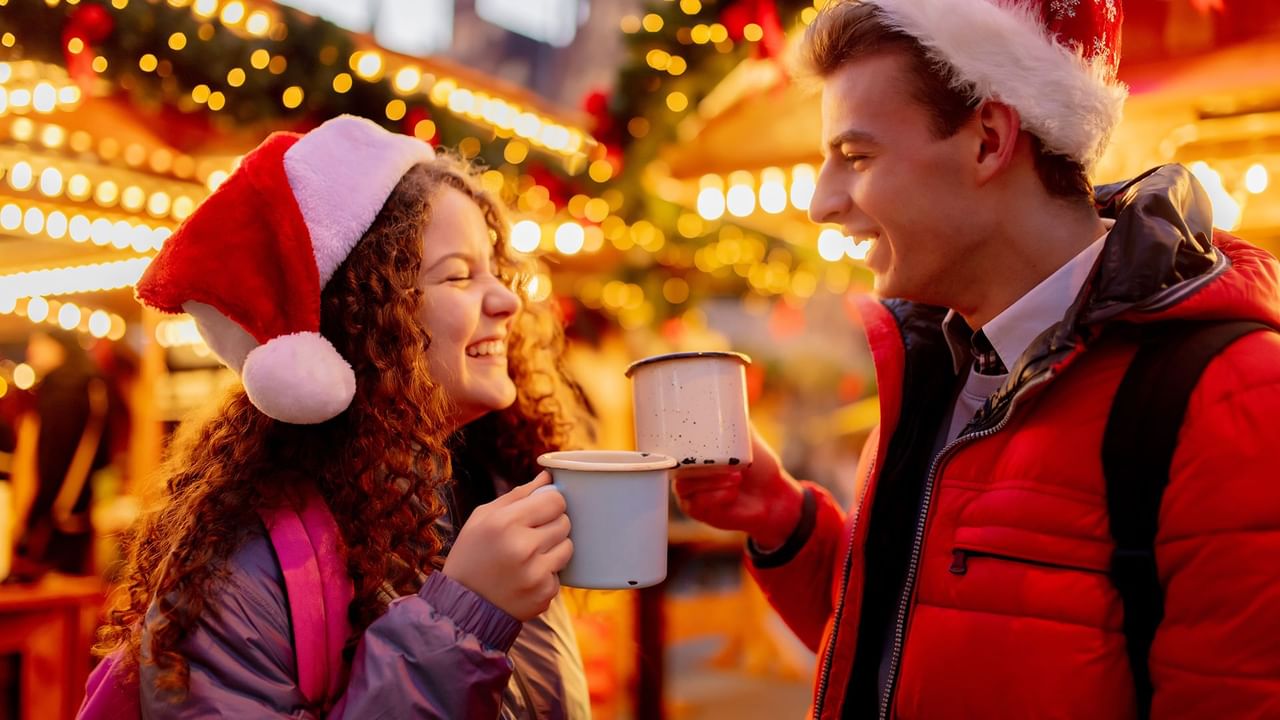 young couple wearing christmas hats holding drinks