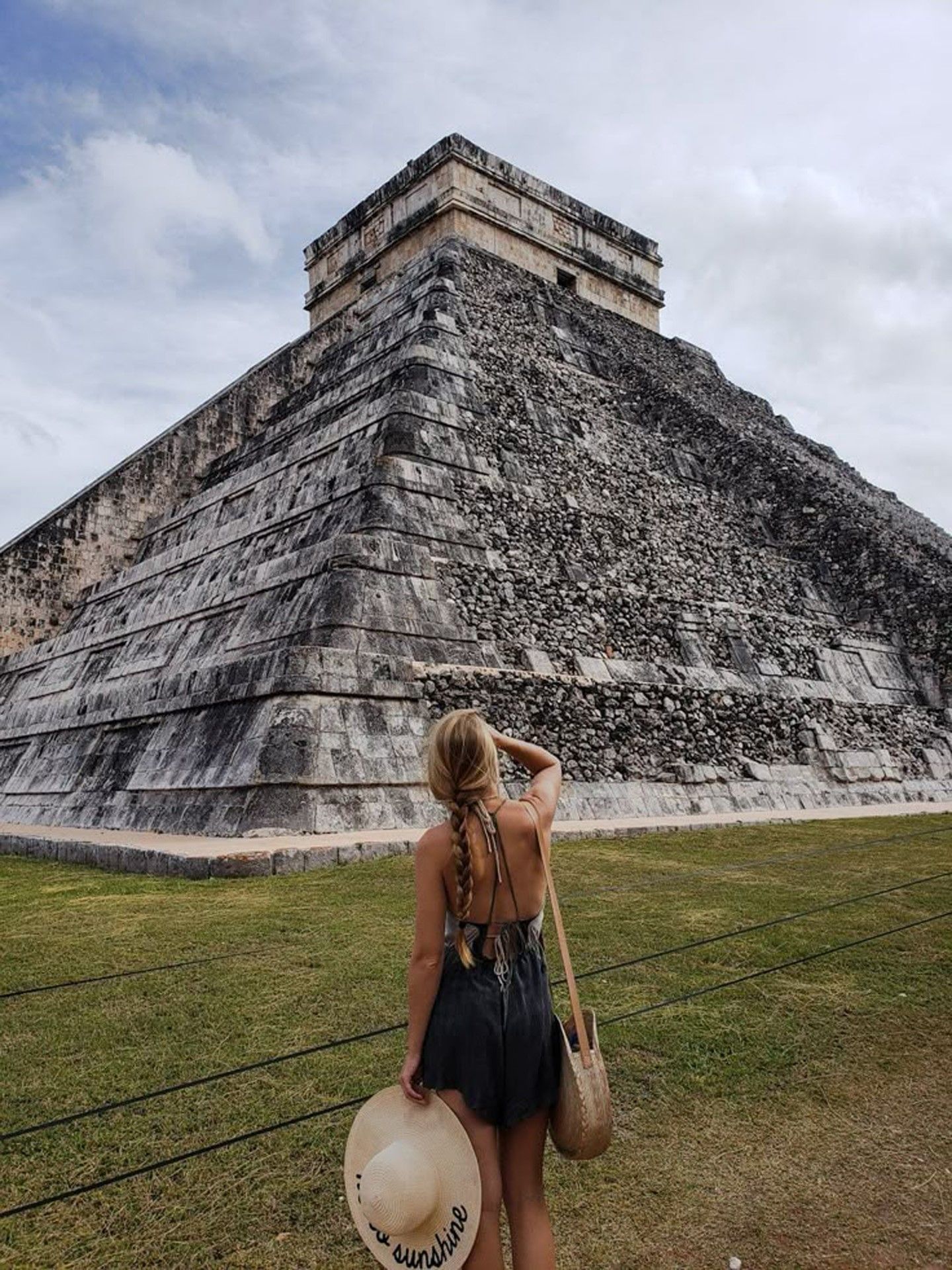 A blonde woman stands with her back to the camera admiring the ancient Mayan pyramid at Chichen Itza near La Zebra Hotel