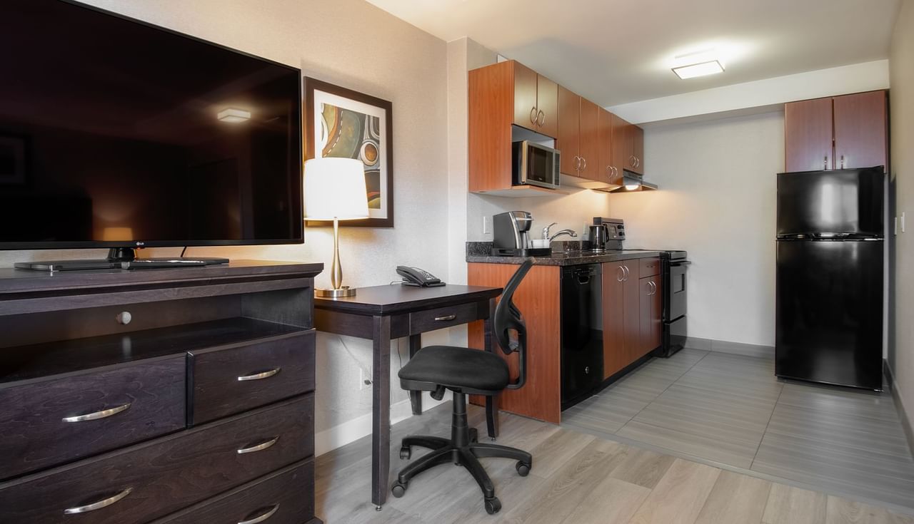 Hotel studio with TV, work desk, chair and a kitchen area