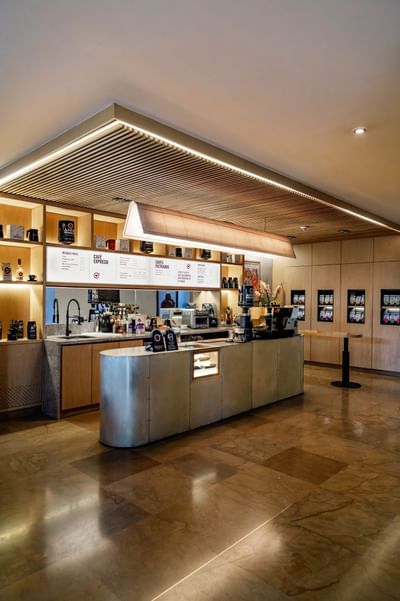 The hotel's modern coffee bar at Habitel Hotel Select with a large counter, a menu board and a tiled floor in Zoe Bar
