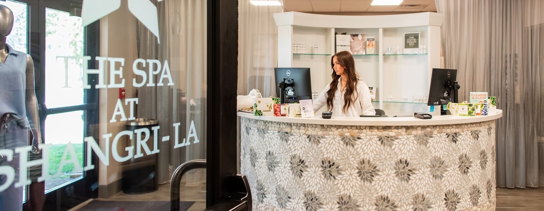 Reception desk at The Spa at Shangri-La Resort featuring a staff member assisting guests in a luxury wellness setting