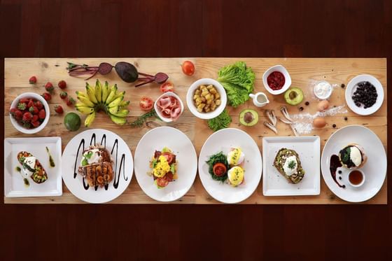 Assorted breakfast dishes and ingredients on a wooden table at Peppers Seminyak.