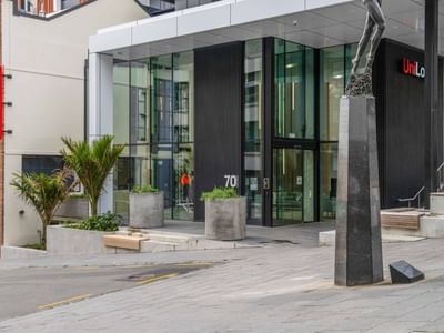 Modern glass entrance with concrete planters and sculpture at UniLodge Auckland Central