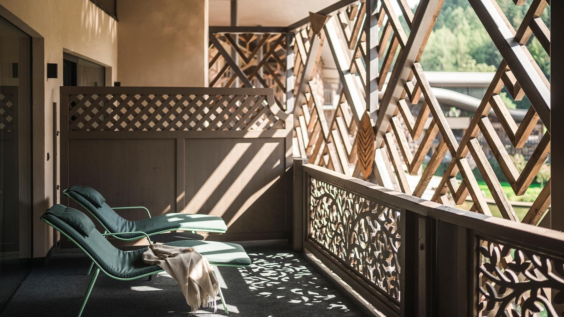Balcony with two green lounge chairs, wooden lattice railings, and a towel draped over one chair.