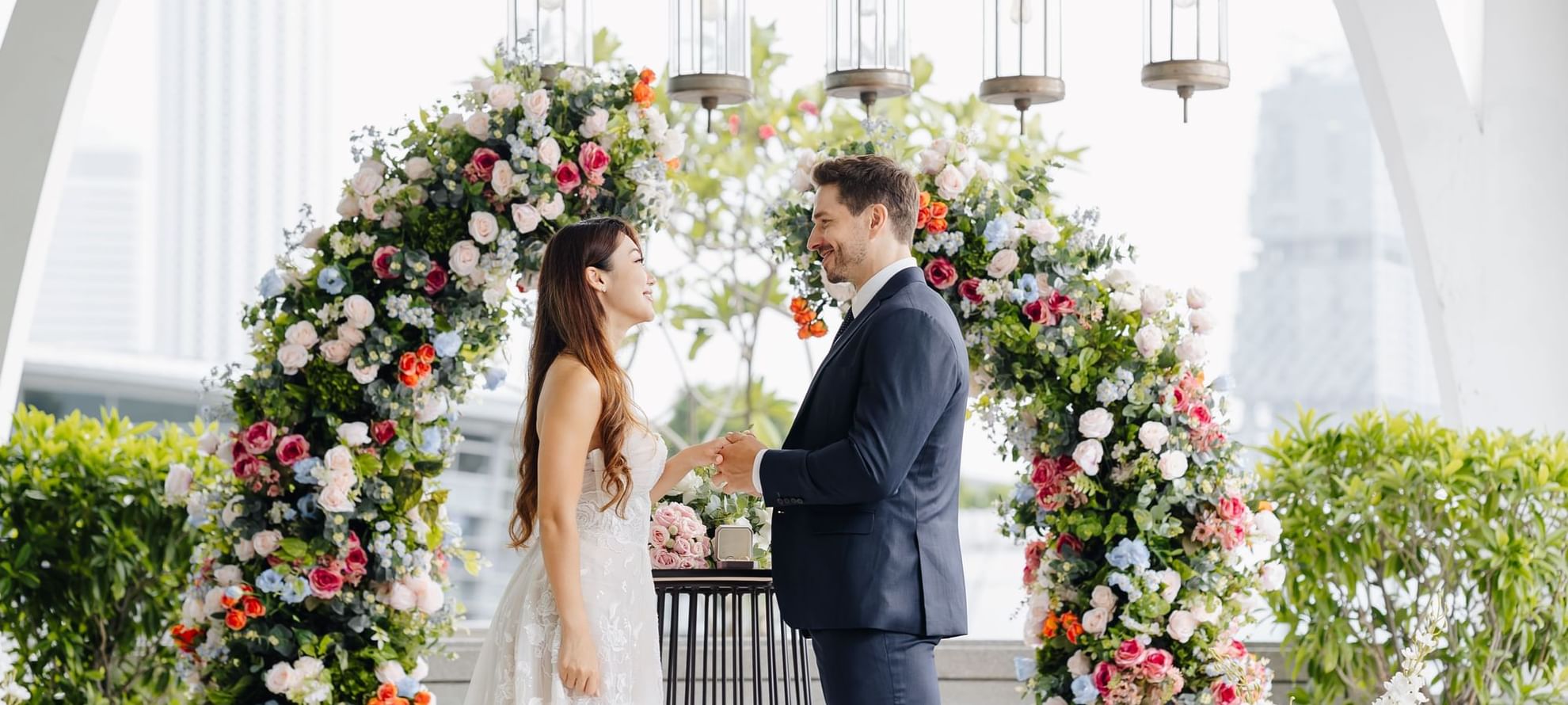 A couple holding hands at their floral decorated wedding ceremony at The Fullerton Bay Singapore