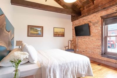 Cozy large bed, flower vase, TV & chair in Executive Residences at Retro Suites Hotel