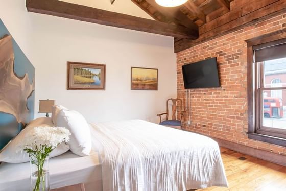 Cozy large bed, flower vase, TV & chair in Executive Residences at Retro Suites Hotel