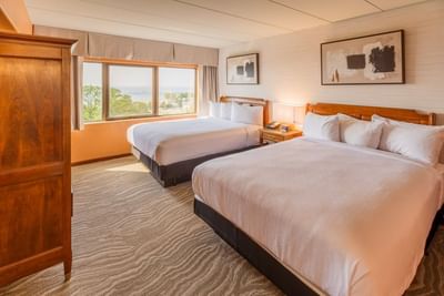 Two beds with a side table by the window and hanging wall art in the room at The Boulevard Inn & Bistro