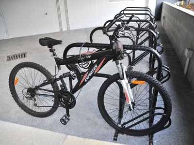 Black bicycle parked at bike rack in the garage at UniLodge Auckland City.