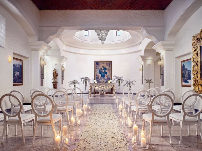 Stunning indoor wedding arrangements at Chapel at Hacienda del Mar Los Cabos, decorated with white rose petals and candles
