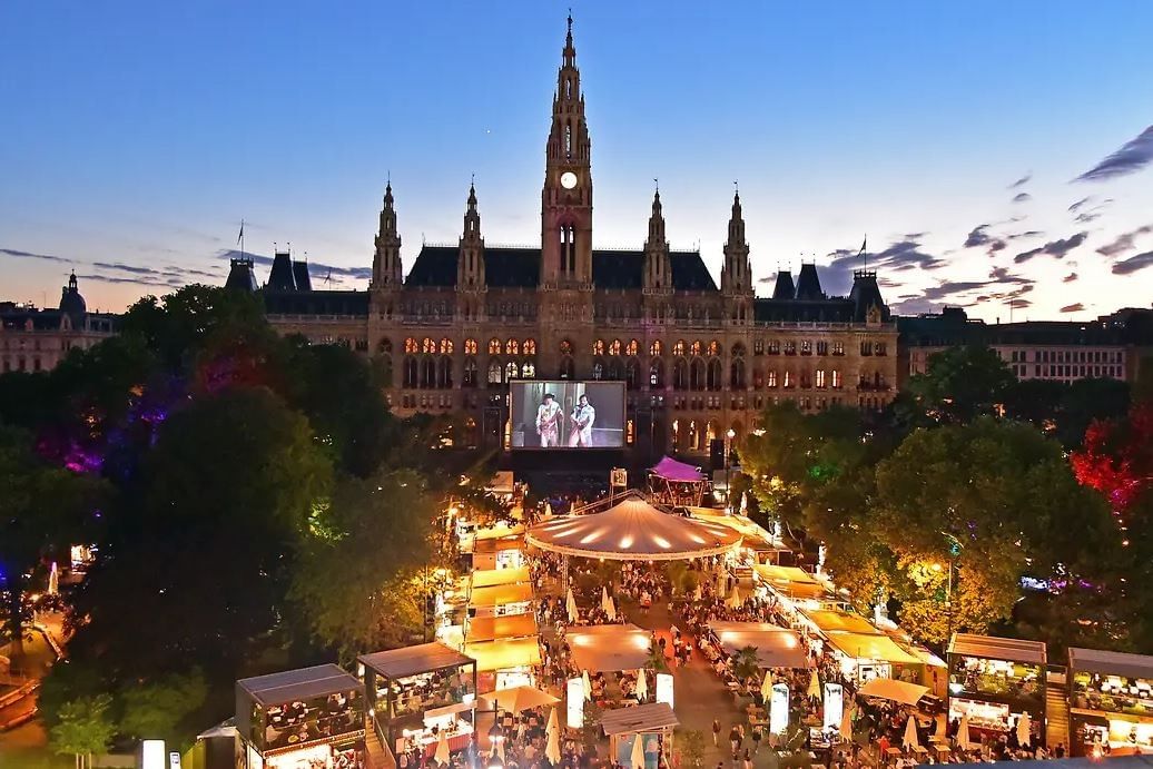 Film Festival am Wiener Rathausplatz bei Abendstimmung mit beleuchtetem Rathaus, Open Air Kino und Gastronomieständen