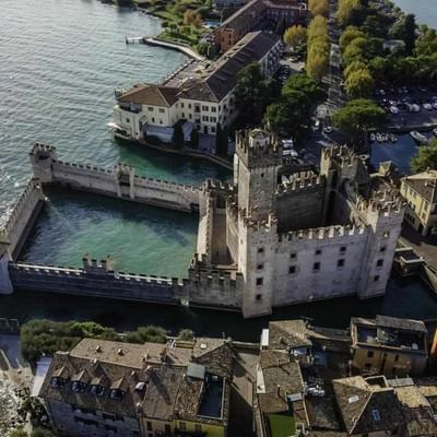 Luftaufnahme der Burg Scaligero umgeben von Wasser und Gebäuden in Sirmione, Italien.
