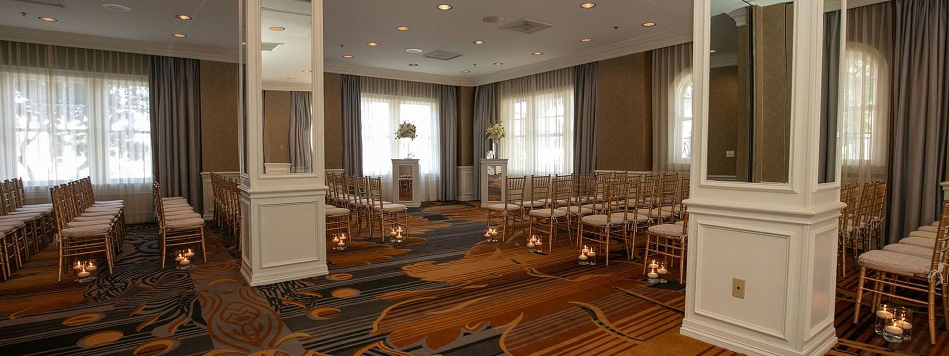 Rows of gold chairs by mirrored pillars under a soft ceiling glow in Oak Lawn/Terrace at Warwick Melrose Dallas