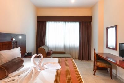 Work desk facing bed with seating by the window in room at Tamani Marina Hotel