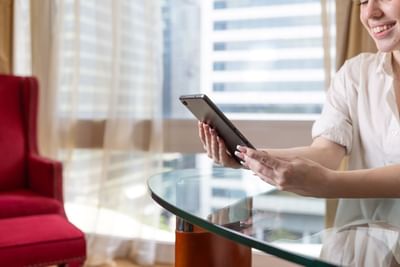A guest relaxes in their room using a tablet, enjoying the modern amenities at the Royal on the Park Hotel