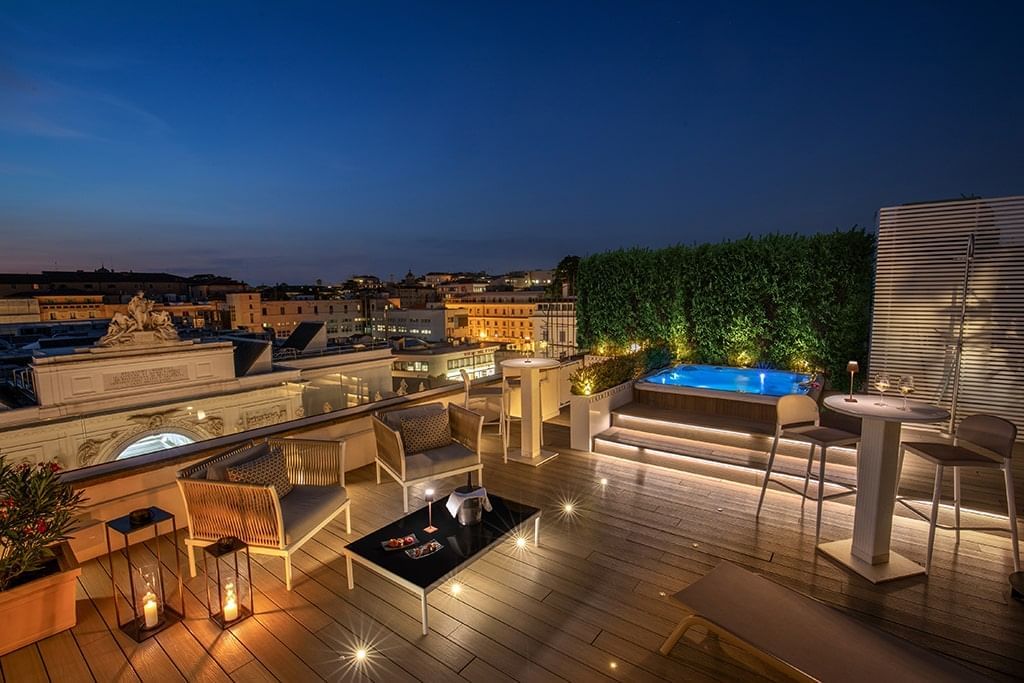 Elegant rooftop terrace at The Glam Hotel with hot tub, cozy seating, soft lighting, and night city views by AG Hotels