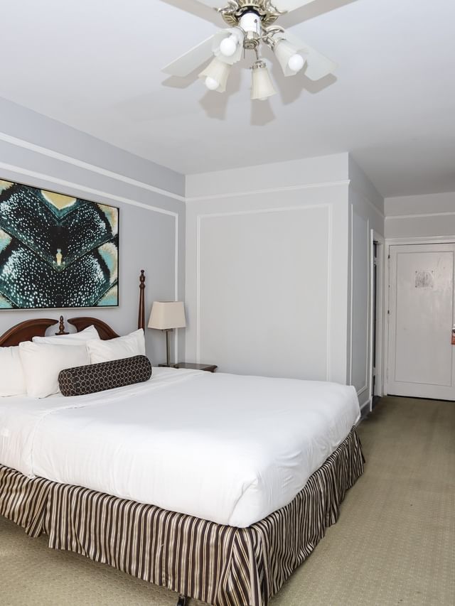 Standard Room at Arlington Resort Hotel & Spa, showing a large bed, wooden dresser, and gold-framed mirror