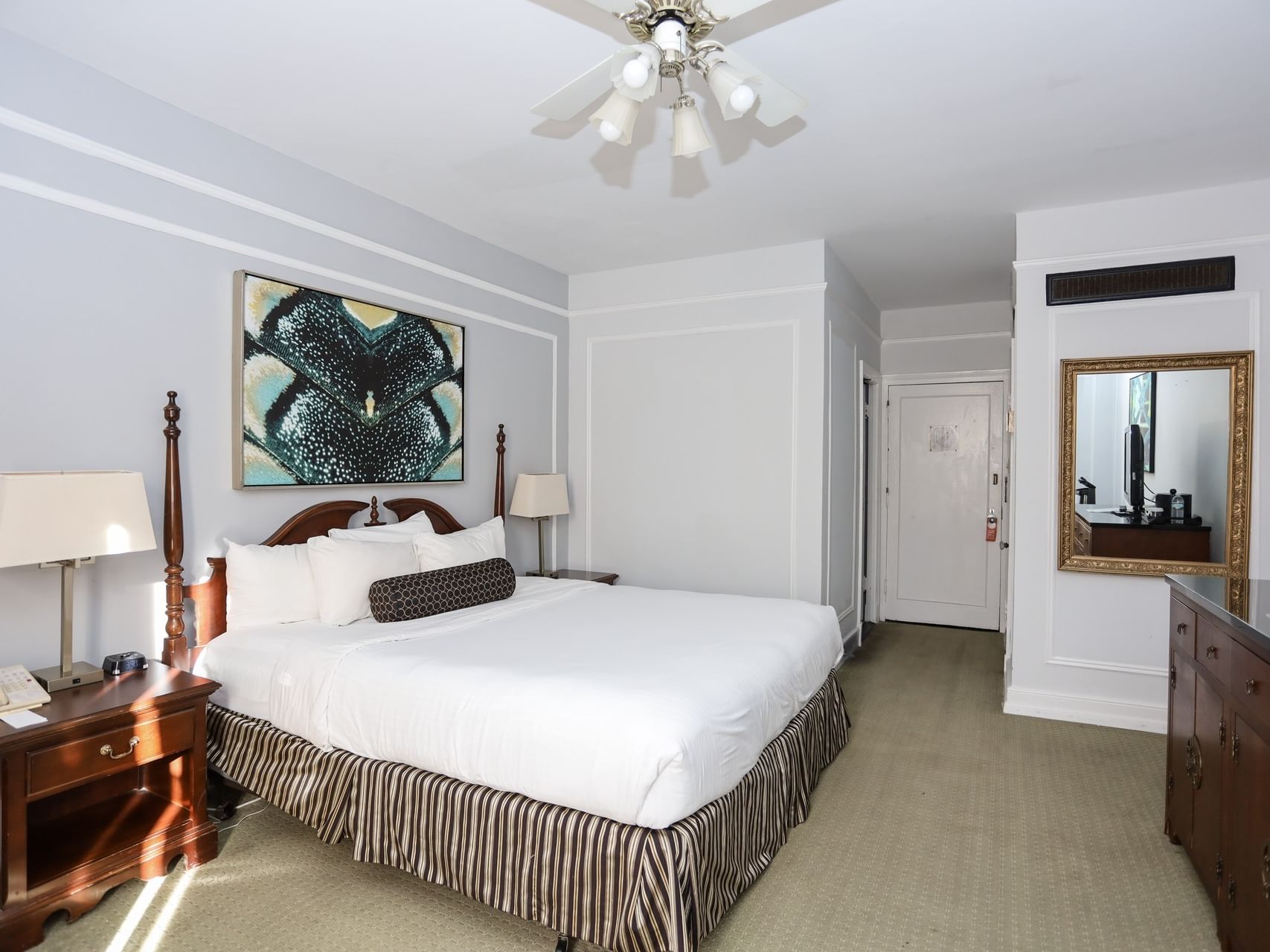 Standard Room at Arlington Resort Hotel & Spa, showing a large bed, wooden dresser, and gold-framed mirror
