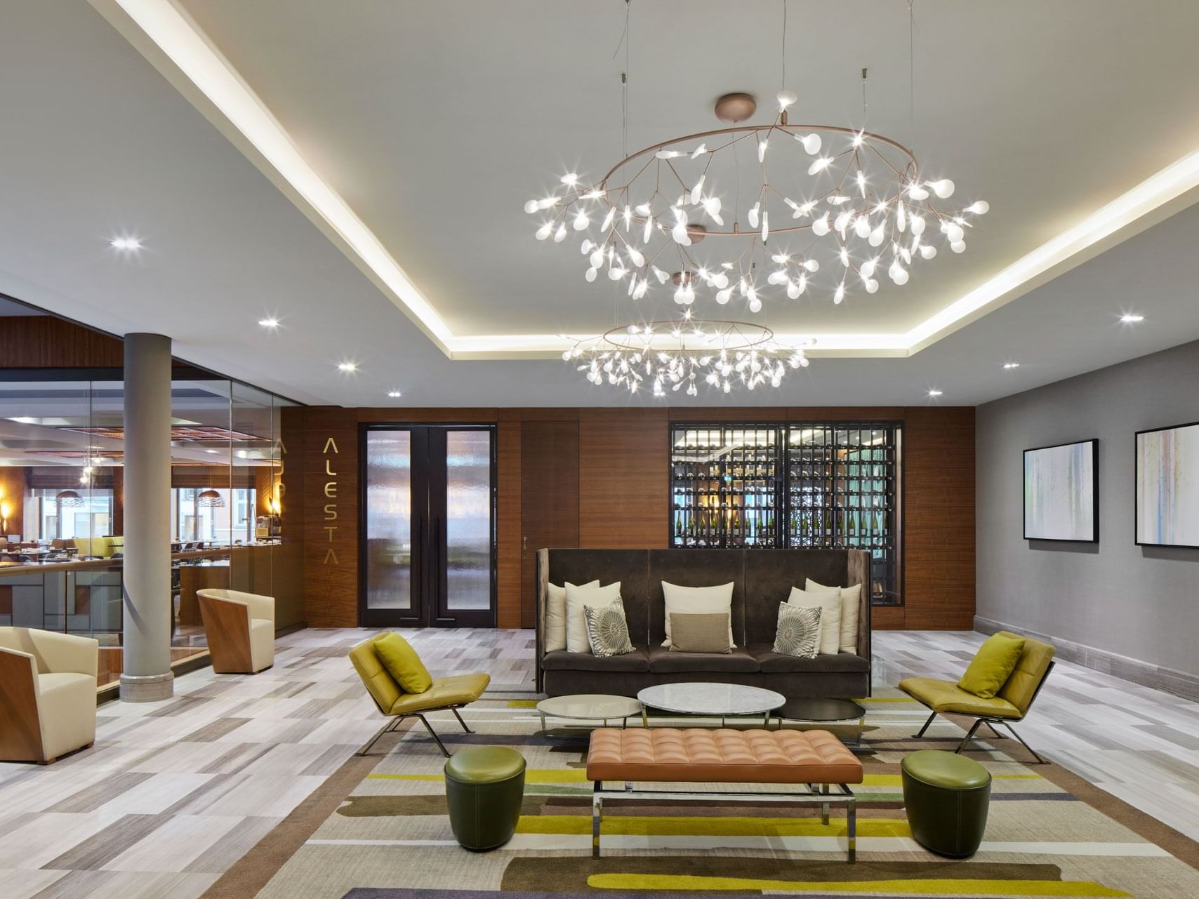 Moderne Hotellobby mit Sitzbereich, Sesseln, Teppich, Kronleuchter und Wandkunst – Titanic Chaussee Berlin.