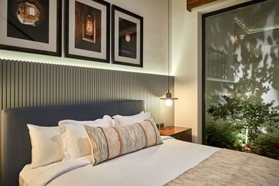 Elegant bedroom with a cozy bed, a wall light, and a glass wall showing an outdoor garden at Singular Signature Residences