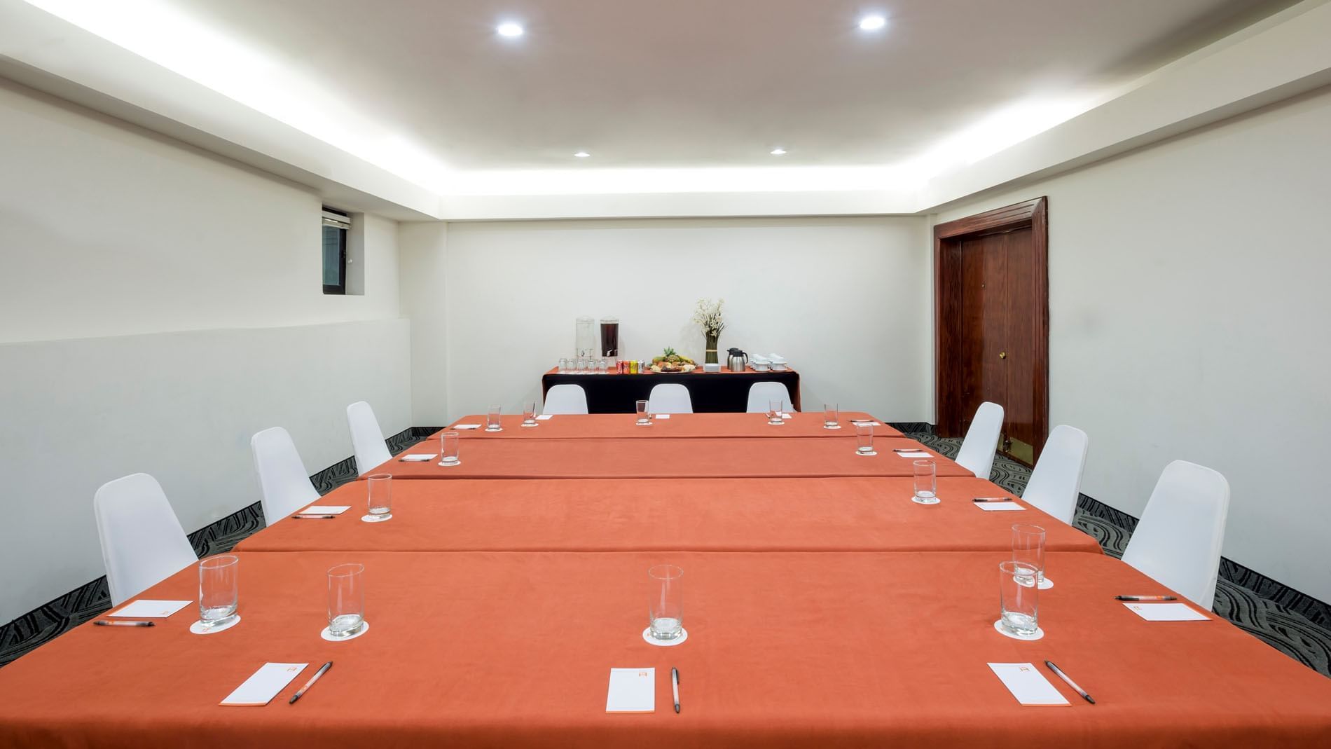 Setup table with a notepad and a water glass by the buffet table near the door in Budapest at Real Inn Mexicali