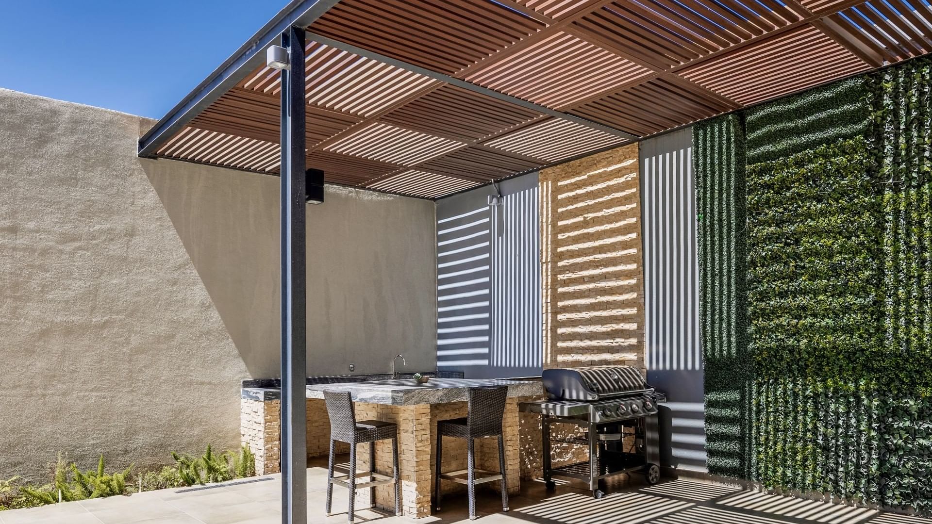 Modern outdoor kitchen with a grill and a green wall at Fiesta Inn Suites Aeropuerto del Bajío