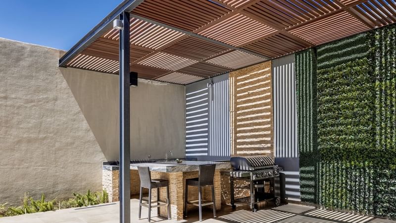 Modern outdoor kitchen with a grill and a green wall at Fiesta Inn Suites Aeropuerto del Bajío