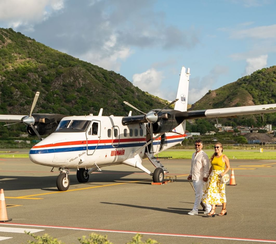 Passengers walking near a Winair twin Otter plane at F. D. Roosevelt Airport on the runway near Golden Rock Resort