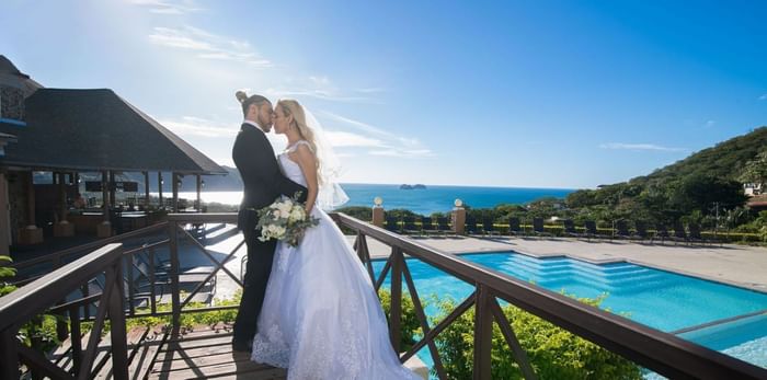 Wedded couple posing by outdoor pool at Villas Sol Beach Resort