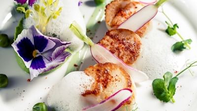 Plat de fruits de mer avec des fleurs, des pois, des radis et une sauce mousseuse.