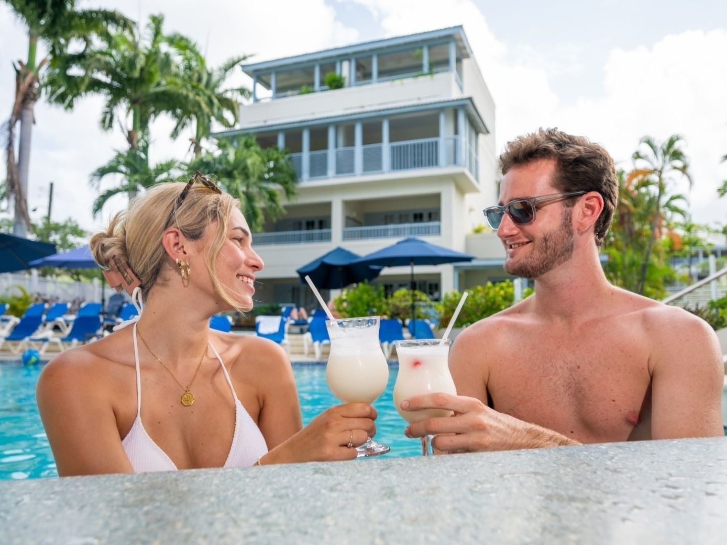 Two people enjoying drinks poolside at Savannah Beach Hotel.