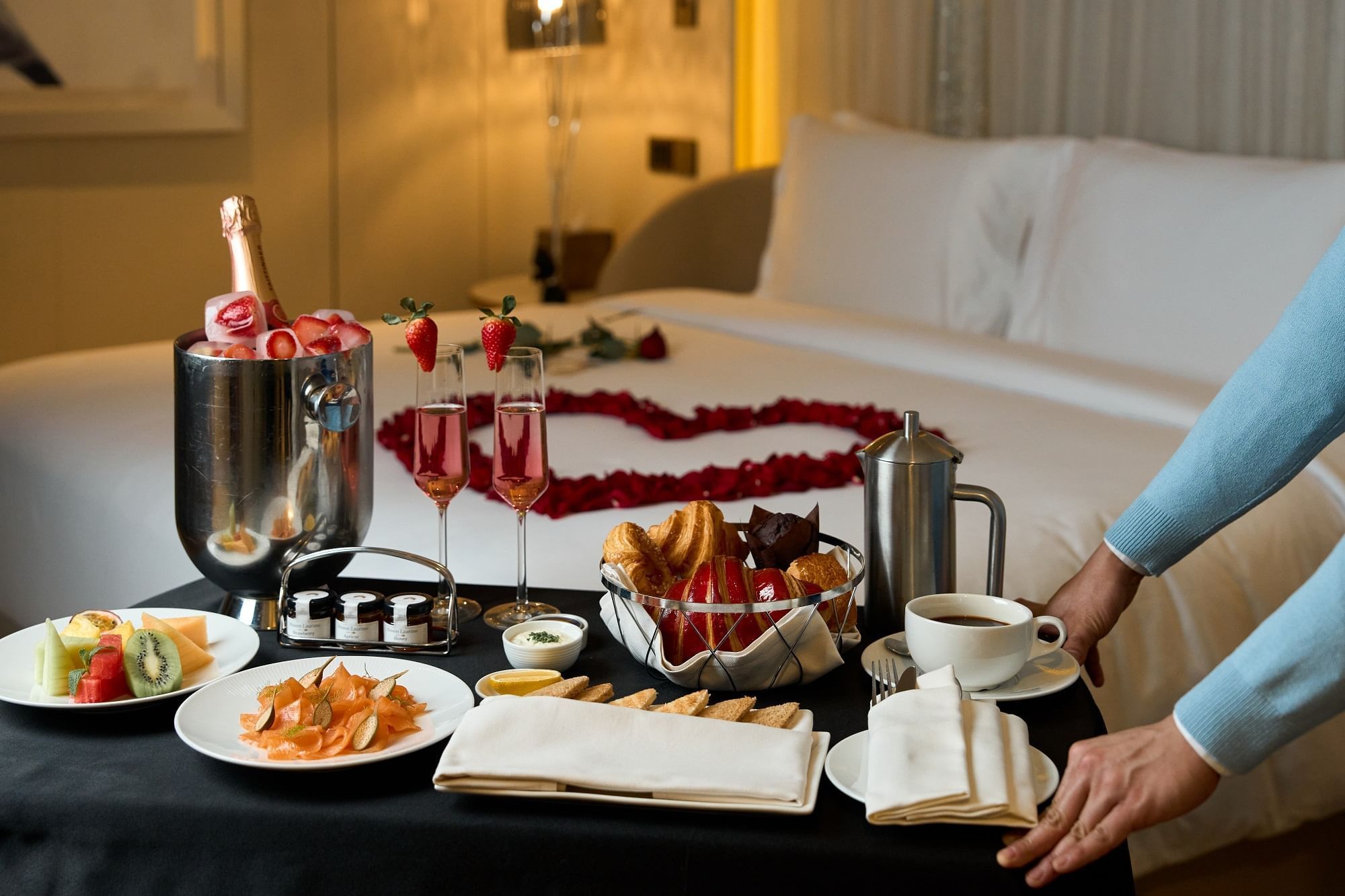 In-room breakfast table served with croissants, fruits, and champagne at Paramount Hotel Dubai