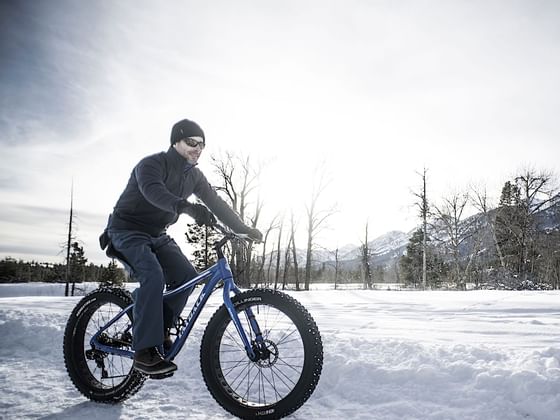 A man riding a fat tire bicycle in the snow near Hotel Jackson